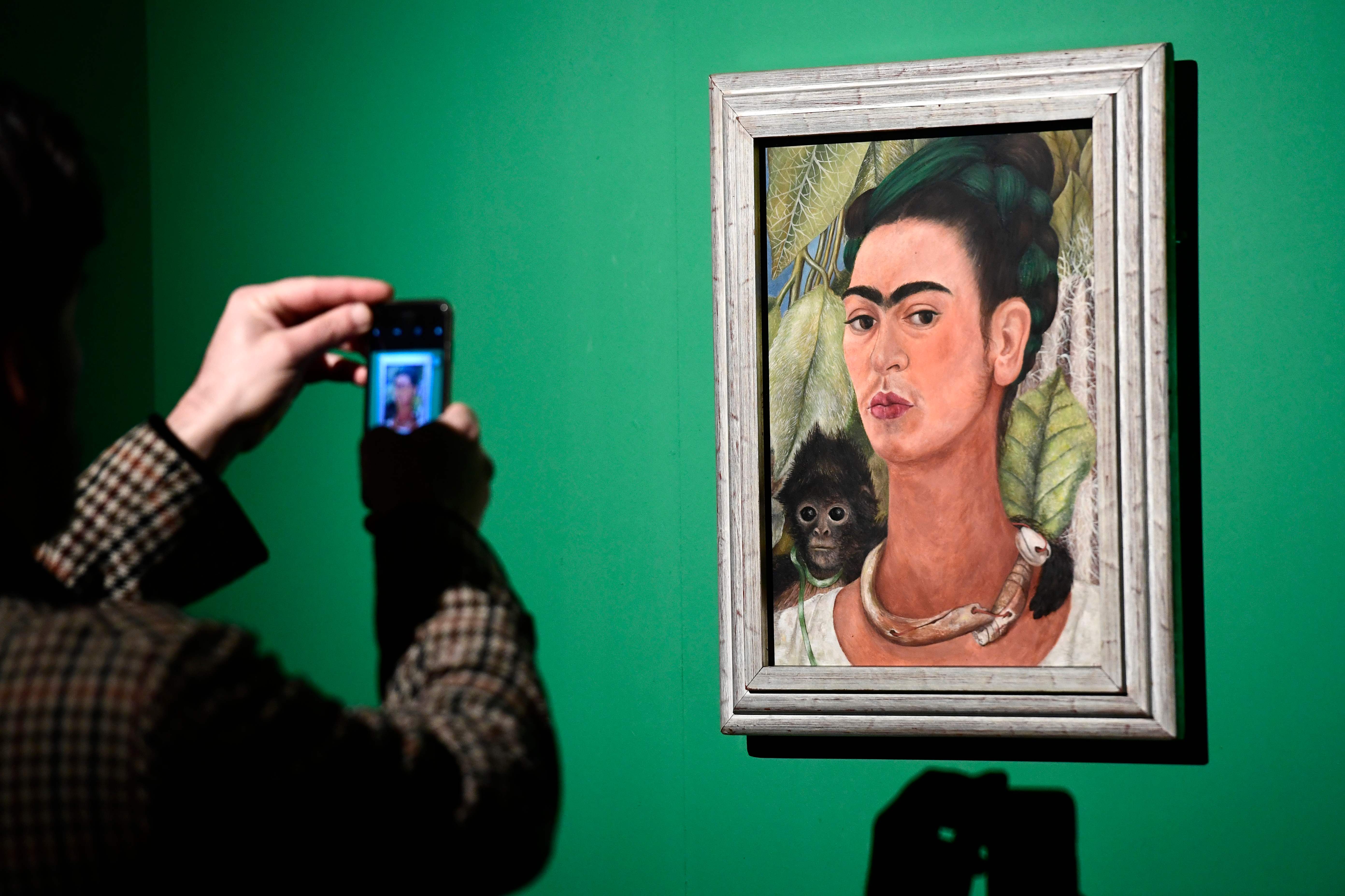 A journalists takes a picture of a painting by Mexican artist Frida Kahlo (1907-1954) called "Self-portrait with Monkey" during a press visit to her exhibition "Oltre il mito" (Beyond the Myth) at the Mudec (Museo delle Culture - Museum of Culture) in Milan on January 31, 2018. The exhibition runs from February 1 to June 3, 2018. / AFP PHOTO / MIGUEL MEDINA / RESTRICTED TO EDITORIAL USE - MANDATORY MENTION OF THE ARTIST UPON PUBLICATION - TO ILLUSTRATE THE EVENT AS SPECIFIED IN THE CAPTION